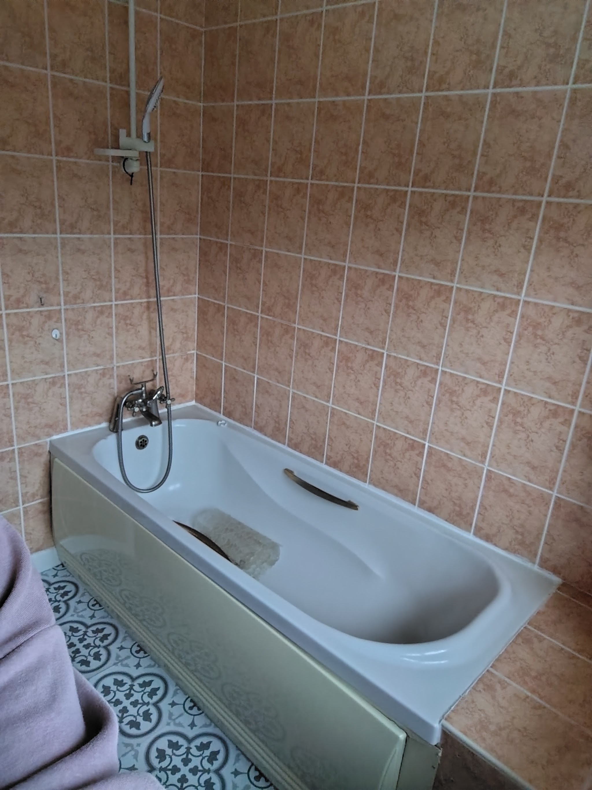Lynn's bathroom before the work, with pink wall tiles and a bath